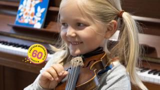Tyttö soittaa viulua kulttuurikeskus Orvokissa. Kuvassa Vantaan musiikkiopiston 60-vuotisjuhlavuoden logo.